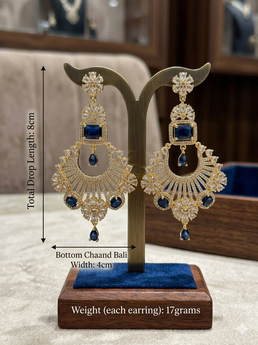 Luxury American Diamond and royal blue sapphire gemstone chaand bali statement earrings in a warm gold finish. Features a floral stud, geometric lattice layers, and hanging sapphire blue teardrop stones, perfect for bridal and wedding wear.