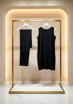 Hanging display of the black handcrafted sleeveless Chanderi silk Chikankari co-ord set, featuring the tunic and trousers hanging side-by-side on white hangers within a warm-lit gold boutique rack.