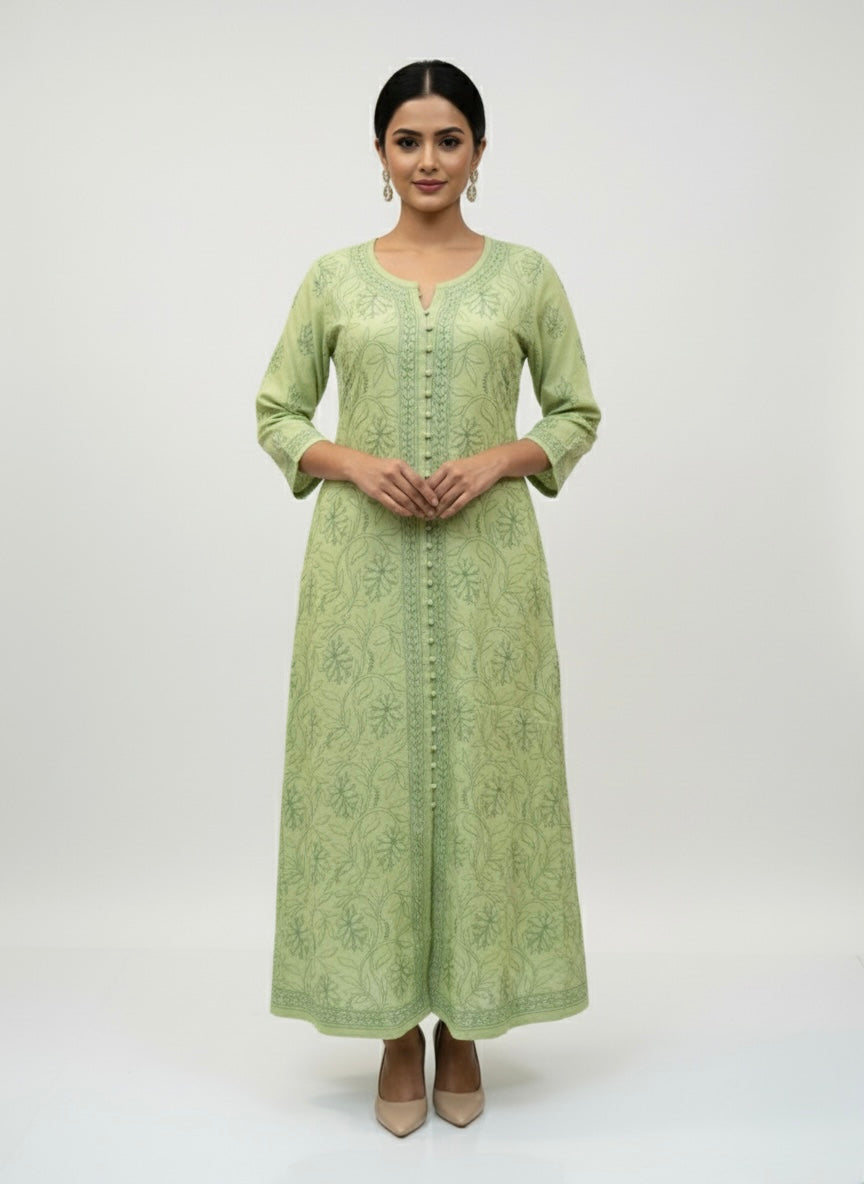 Olive green dress with floral patterns on a grey surface with small decorative items.