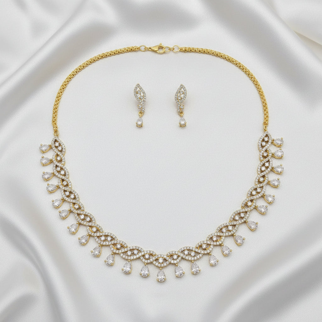 Gold-tone necklace and matching drop earrings set with clear teardrop-shaped stones, displayed on a gray jewelry presentation tray.