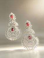 Ornate earrings with red gemstones on a gradient background
