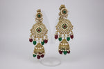 Ornate gold earrings with green and red stones on a black background
