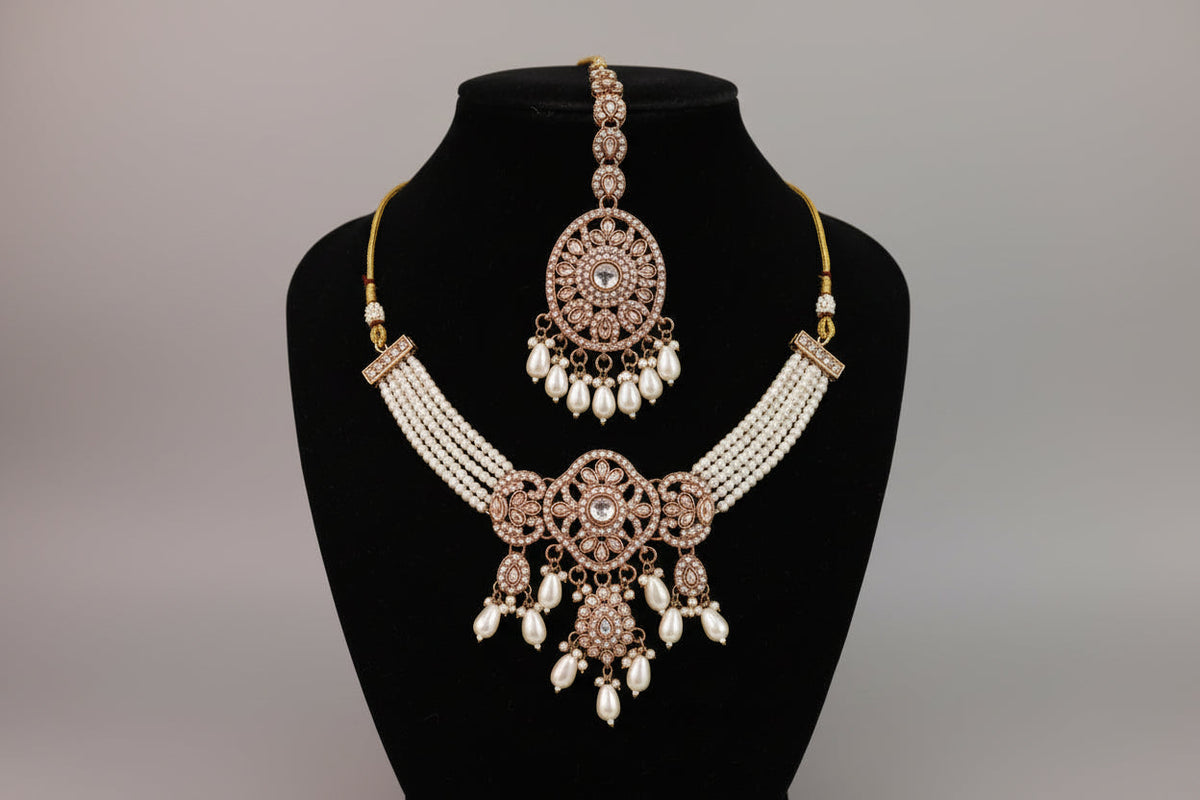 Ornate necklace set on a black mannequin against a grey background