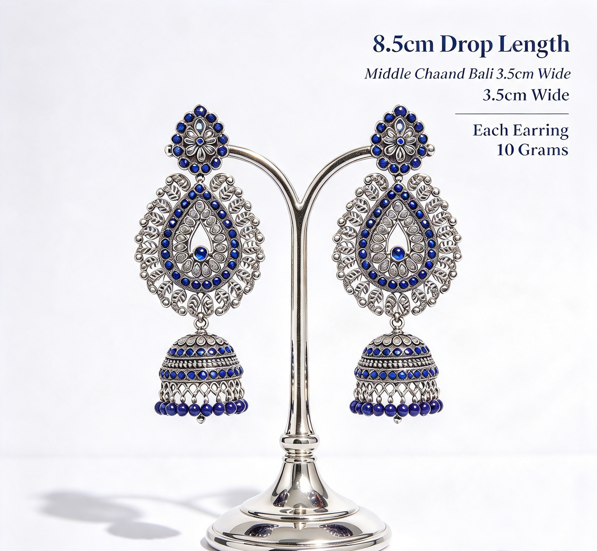 Pair of oxidised silver peacock teardrop jhumka earrings on silver display stand with dimensions — 8.5cm drop, 3.5cm width, 10g each, sapphire navy blue stones, premium bridal jewelry.