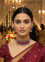 Necklace and earrings set with pink and silver design on a black stand.