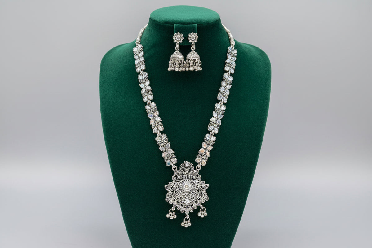 Oxidised long necklace with a pendant in the bottom and small jhumkey earrings with flower stud on top of the jhumkey. 