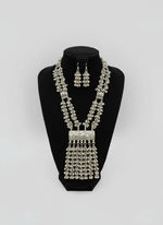 Silver necklace and earrings set on a black mannequin bust with a blurred background