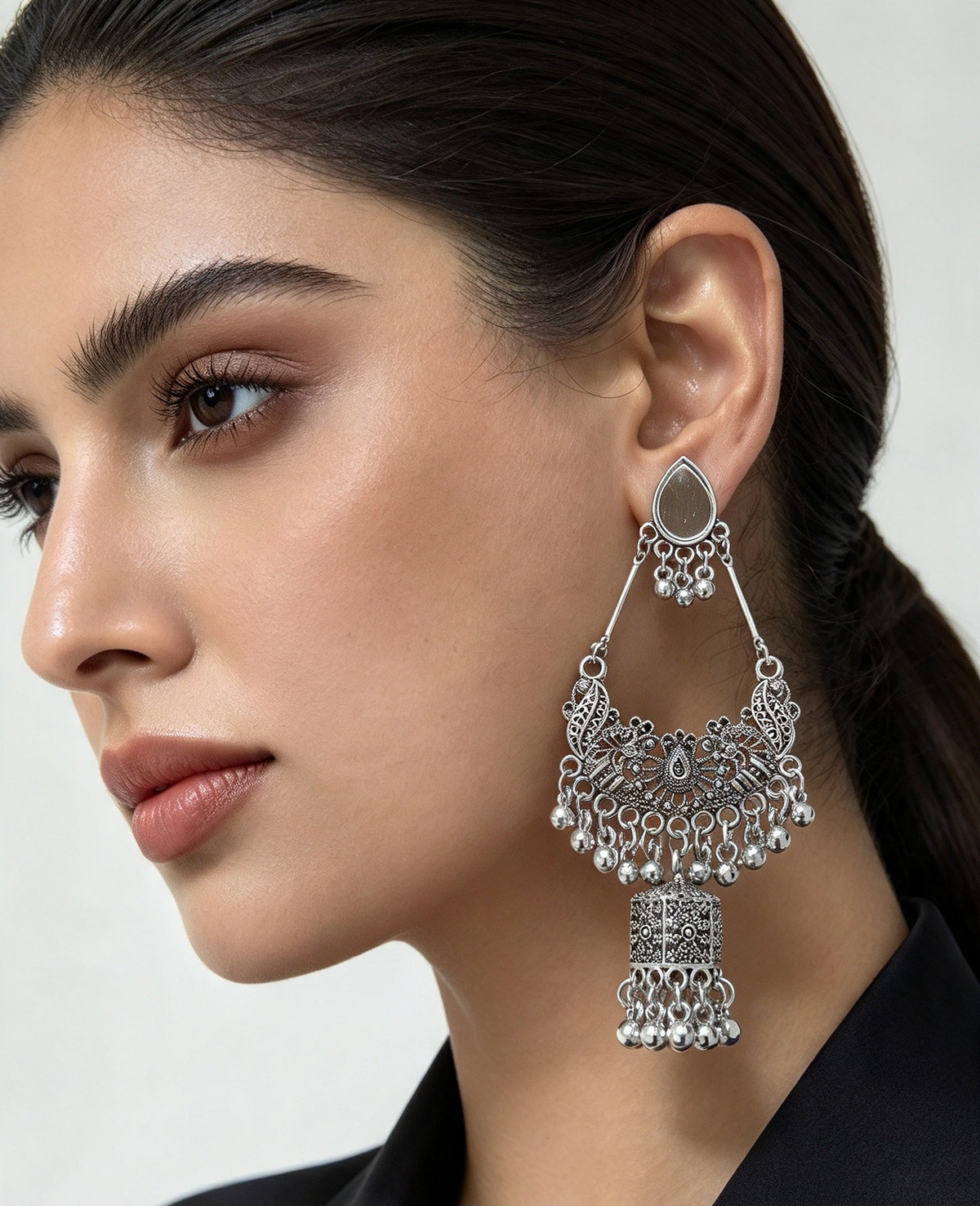 Close-up of woman wearing oxidized silver tone chandbali jhumka earring — intricate filigree work, teardrop top, cascading ghungroo beads, lantern drop, traditional Pakistani Indian ethnic bridal jewelry.