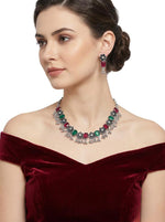 Model wearing the oxidized floral necklace and matching earrings featuring pink and green stone accents and a traditional silver lattice design.