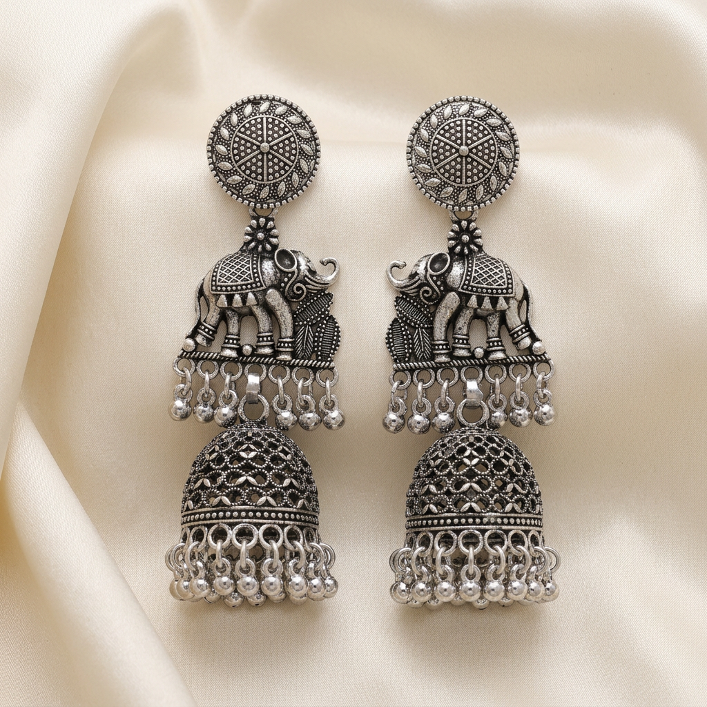 Close-up of a Royal Parade silver-toned elephant jhumka earring on soft beige fabric, showing the elephant motif and beaded dome