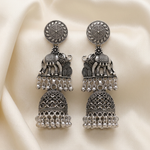 Close-up of a Royal Parade silver-toned elephant jhumka earring on soft beige fabric, showing the elephant motif and beaded dome