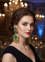 Pair of gold and green gemstone earrings on a textured surface