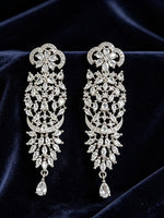 Pair of ornate diamond earrings on a dark fabric background