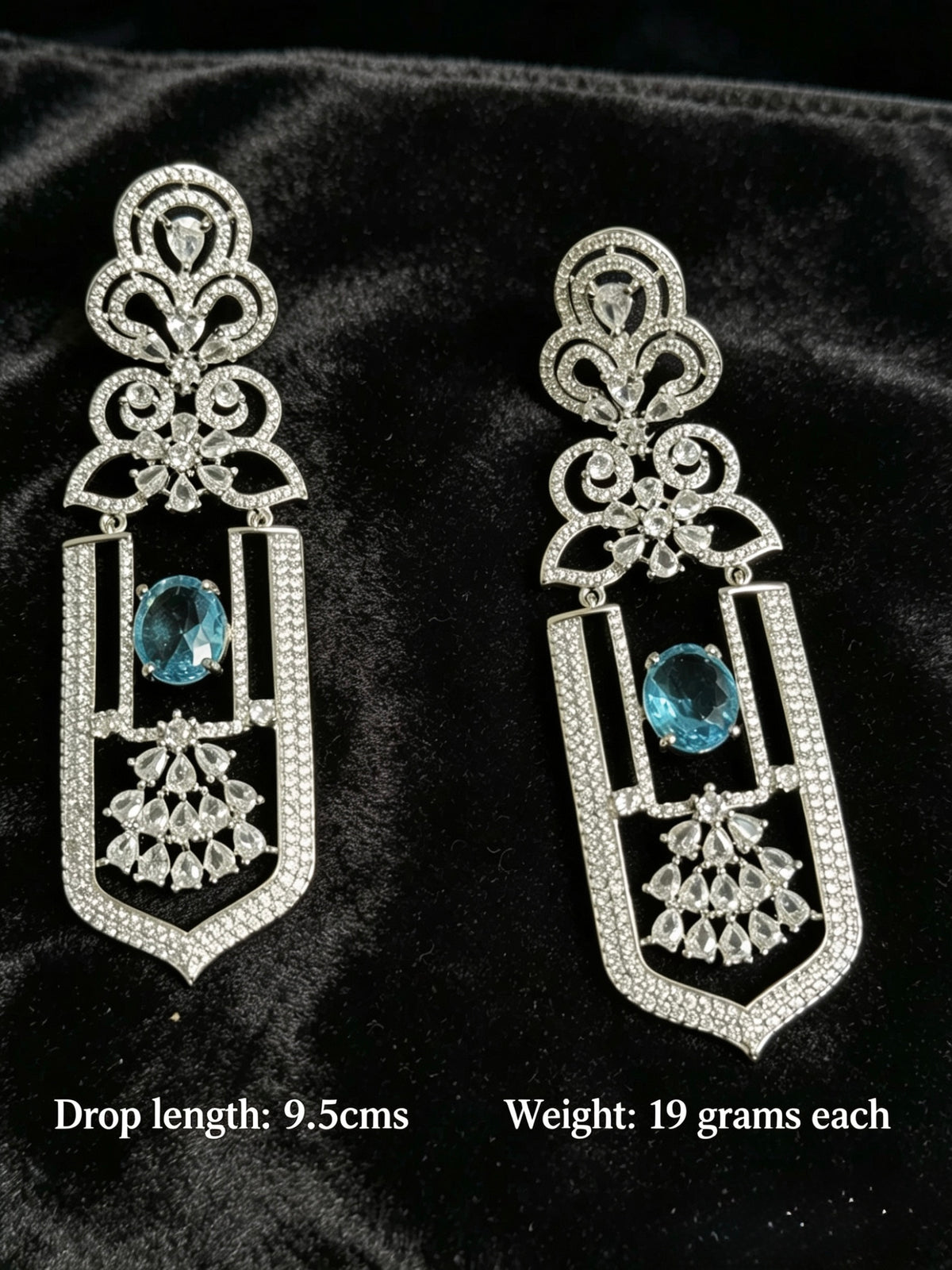 Pair of ornate earrings with blue gemstones on a black background
