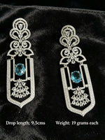 Pair of ornate earrings with blue gemstones on a black background