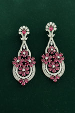 Pair of ornate earrings with floral designs on a black background