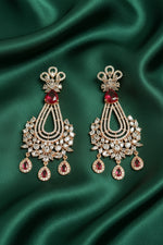 Pair of ornate earrings with red gemstones on a black card against a black background