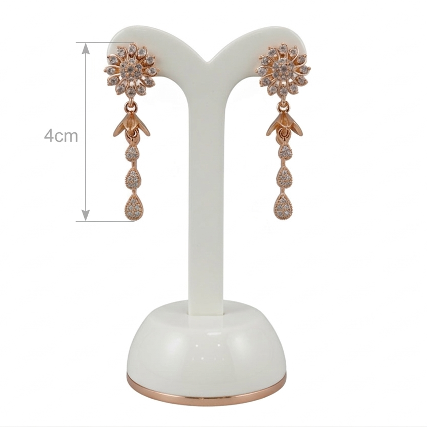 Pair of rose gold earrings on a white stand with measurement label