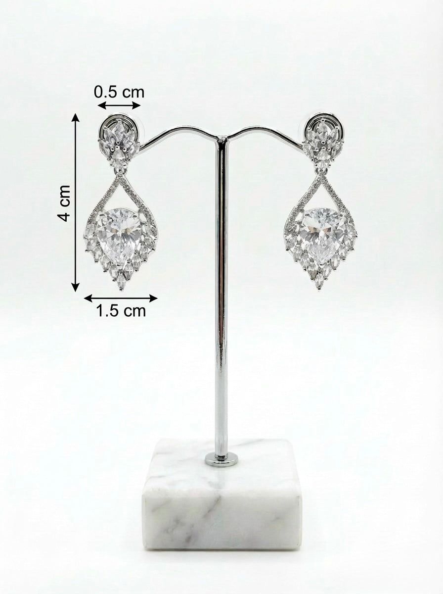 Pair of silver teardrop earrings on a white marble stand with measurements indicated.