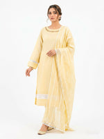 A model wearing a pastel yellow 3-piece cotton salwar kameez suit with a matching sheer dupatta. The kurta features geometric cutout embroidery along the neckline, pleated sleeves, and a white lace insert at the hem.