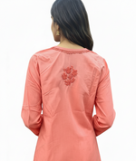 Back view of a peach cotton short kurti featuring delicate chikankari floral embroidery at the upper back and decorative stitching along the neckline.