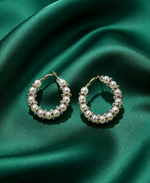 Pearl & clear crystal cluster hoop earrings, gold-tone lever-back, creamy white pearls with sparkling silver-toned crystal accents — resting on luxurious emerald green silk satin.