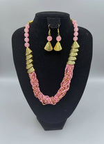 Pink beaded necklace with gold accents and matching earrings on a posh jewellery dummy.
