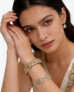 A young woman modeling a pair of traditional dual-tone gold and silver floral lattice bangles accented with American Diamonds, highlighting the elegant design on the wrist.