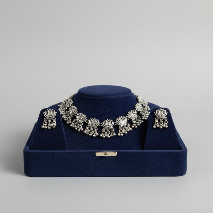 Premium silver oxidised lotus floral choker set on a display stand, highlighting the high-grade antique polish and intricate artisanal craftsmanship.