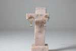 Professional shot of the Aura white stone statement studs on a display stand, highlighting the leaf-like stone arrangement.