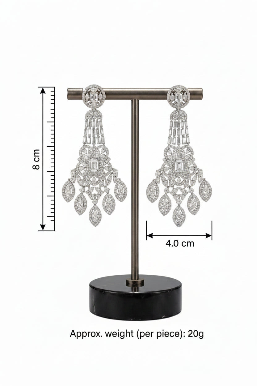A pair of intricate silver-tone crystal chandelier statement earrings displayed on a T-bar jewelry stand with a black marble base.
