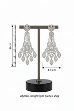 A pair of intricate silver-tone crystal chandelier statement earrings displayed on a T-bar jewelry stand with a black marble base.