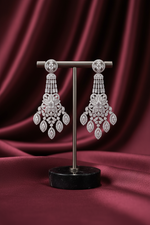 Pair of chandelier earrings on a stand against a burgundy fabric background