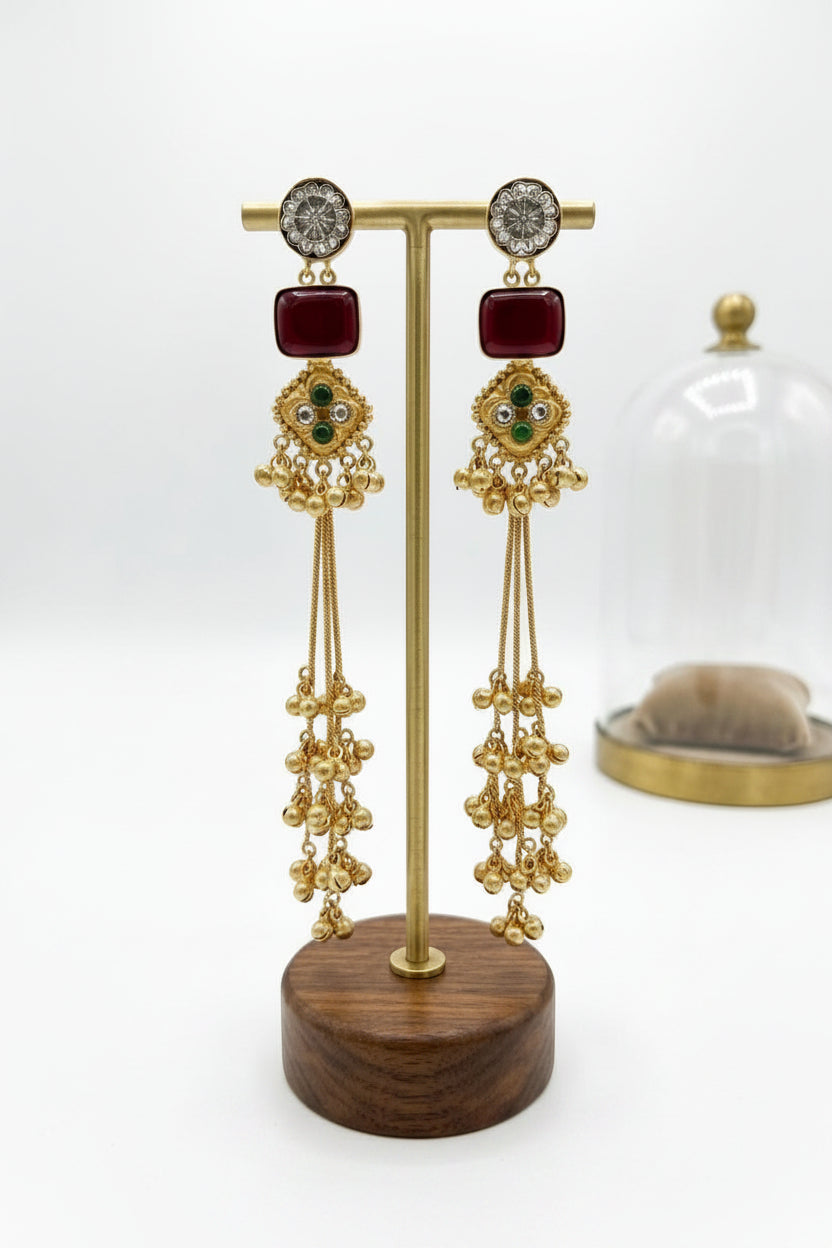  Regal gold laurel leaf drop earrings finished with a deep maroon cushion-cut stone.