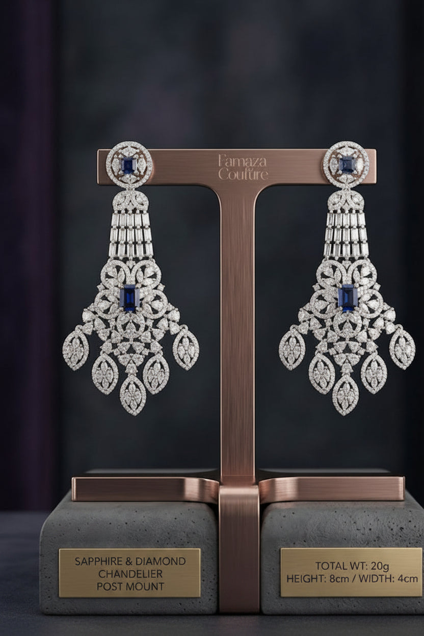 A detailed product photo of a single rose gold chandelier earring with an ornate, multi-tiered design, featuring numerous pavé-set clear diamonds and two prominent deep-blue cushion-cut sapphires, displayed against a dark background, with dimensions text at the bottom.