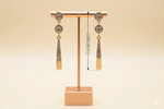 Rose Gold earrings with AD white stones on a stand with measurement label against a beige background