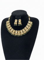 Gold necklace and earrings set on a black mannequin bust against a white background