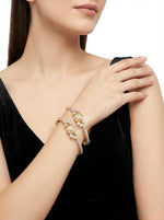 A woman wearing the Royal Peacock American Diamond hinged bangles, showcasing the luxury gold-plated finish and floral design against a black dress.