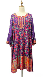Close-up photograph of a deep purple long kurti featuring detailed multi-color floral print and embroidered neckline.