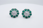 A pair of round floral cluster stud earrings featuring green emerald-cut gemstones and a central clear round stone in a silver-toned setting, displayed on a clean white background.
