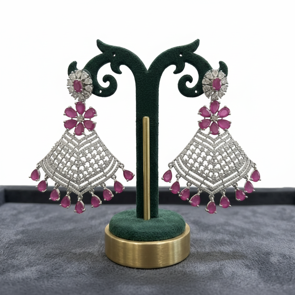 Pair of silver and pink earrings on a green stand with a gray background