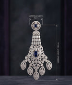 A detailed studio shot of an ornate chandelier earring featuring pavé-set diamonds and two deep blue sapphires, displayed on a stand against a black background, with specifications listing a 8 cm drop, 4 cm width, and 20-gram weight.