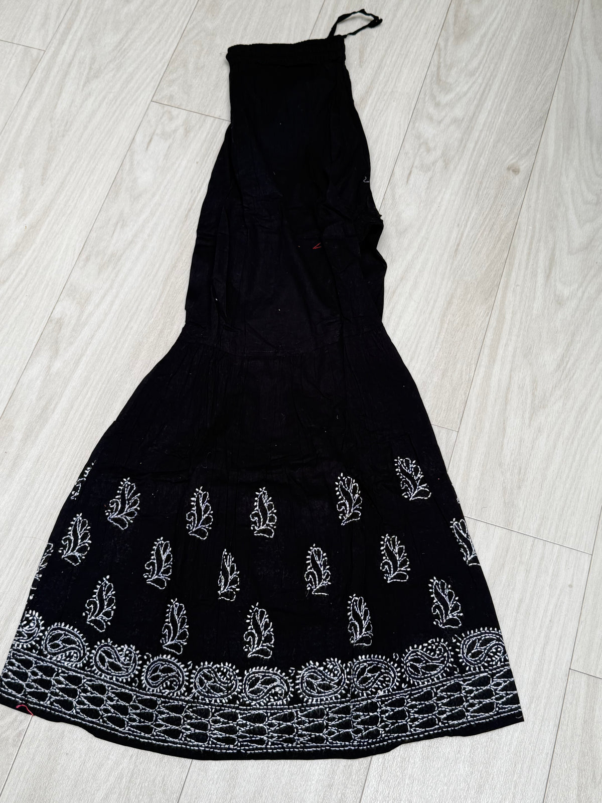 Sharara with white thread bakhiya embroidery is shown as folded in double layer. Focus is embriodery.