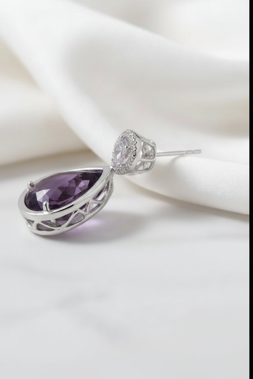 Side view of an amethyst teardrop earring in a rose gold setting, shown with its accompanying soft silicone earring backs.