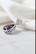 Side view of an amethyst teardrop earring in a rose gold setting, shown with its accompanying soft silicone earring backs.