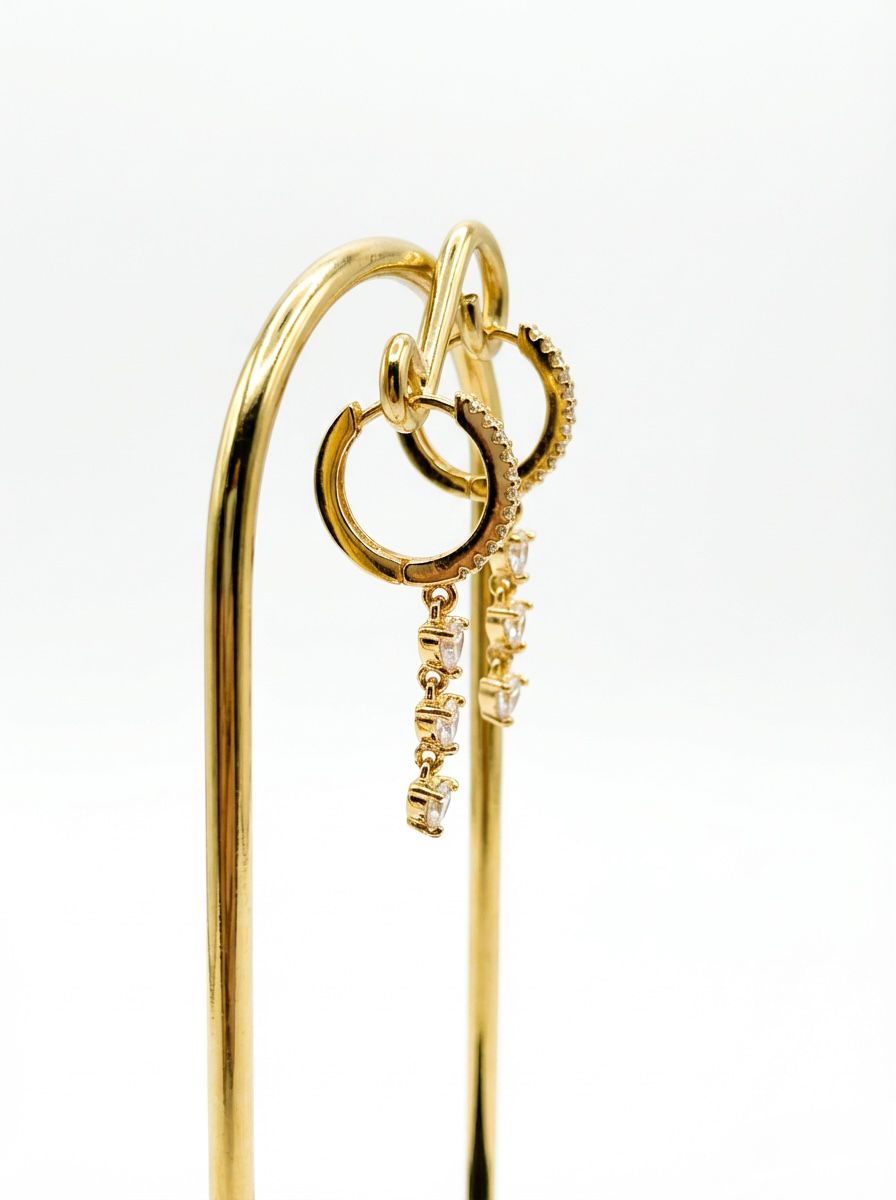 Side view of gold-plated hoop earrings featuring a sparkling dangling chain of crystals.