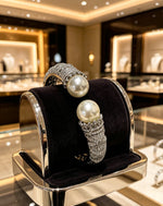 Silver Open Cuff Bangle with Large Pearls & Sparkling Crystals — luxury pearl and crystal bracelet displayed on premium jewelry stand in boutique
