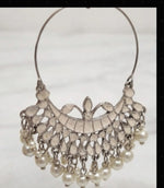 A pair of elegant, silver-toned Chaand Bali drop earrings with intricate lattice detailing and dangling pearl beads, displayed on a black velvet stand against a white marble background.