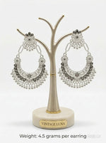 Silver-toned evening earrings with a wide, decorative silhouette and textured filigree design.