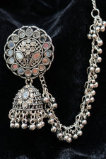 An ornate silver-toned traditional Indian jhumka necklace with intricate filigree work, circular stone inlays, and dangling bell-shaped charms, displayed on a black background.